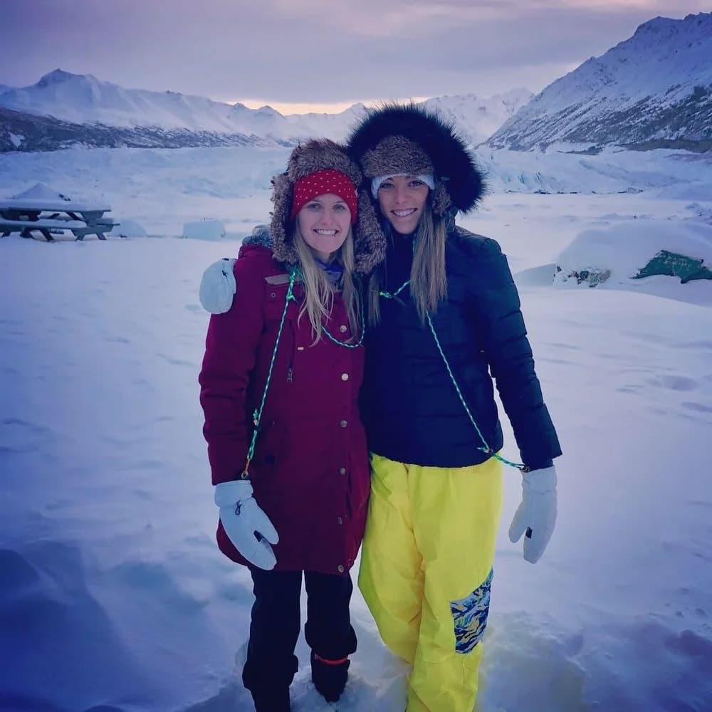 Rachelle and Taylor together in Alaska, bundled in winter gear with a glacier and mountains behind them